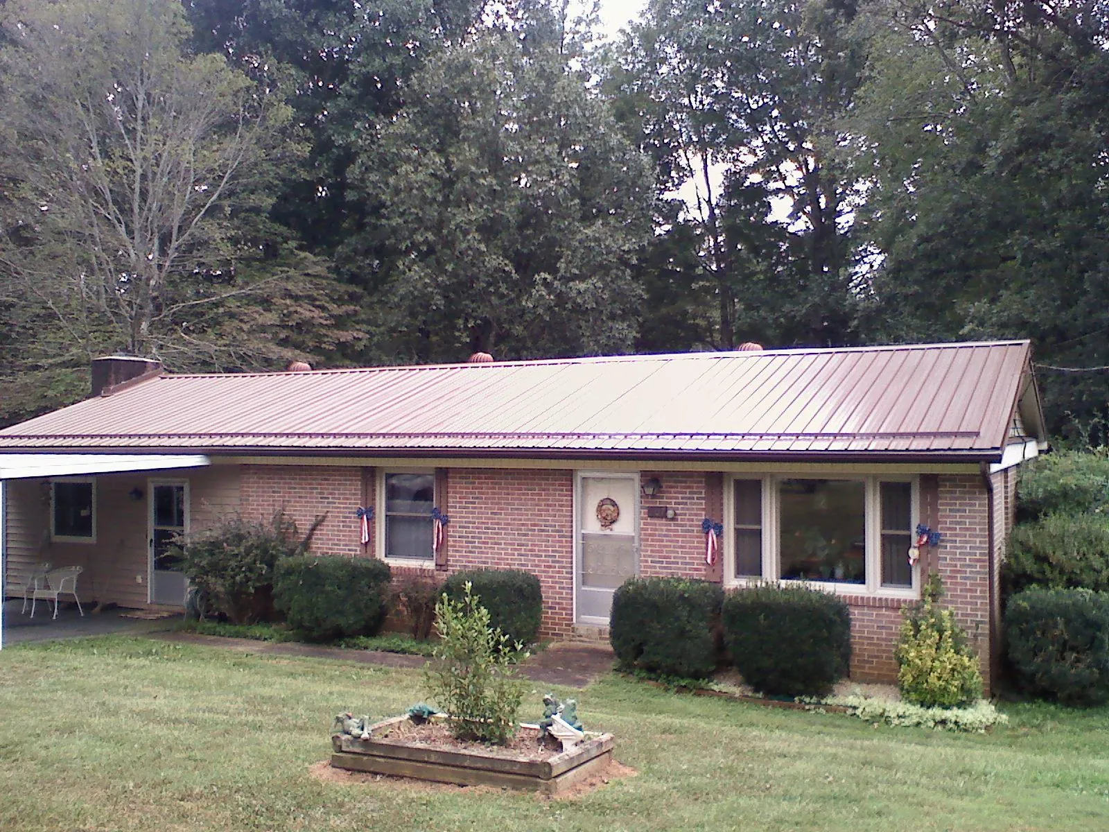 Bronze metal roof on a brick ranch home with a carport in Ridgewood