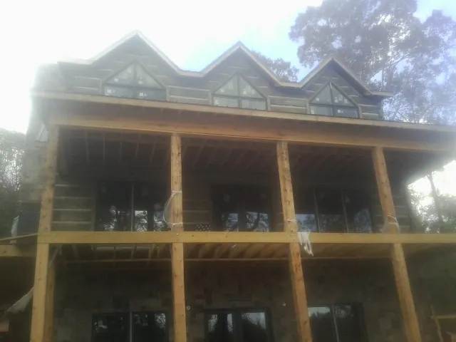 Dormers and porch framing on a large log home under construction — Roof Coating work by our crew in Ridgewood