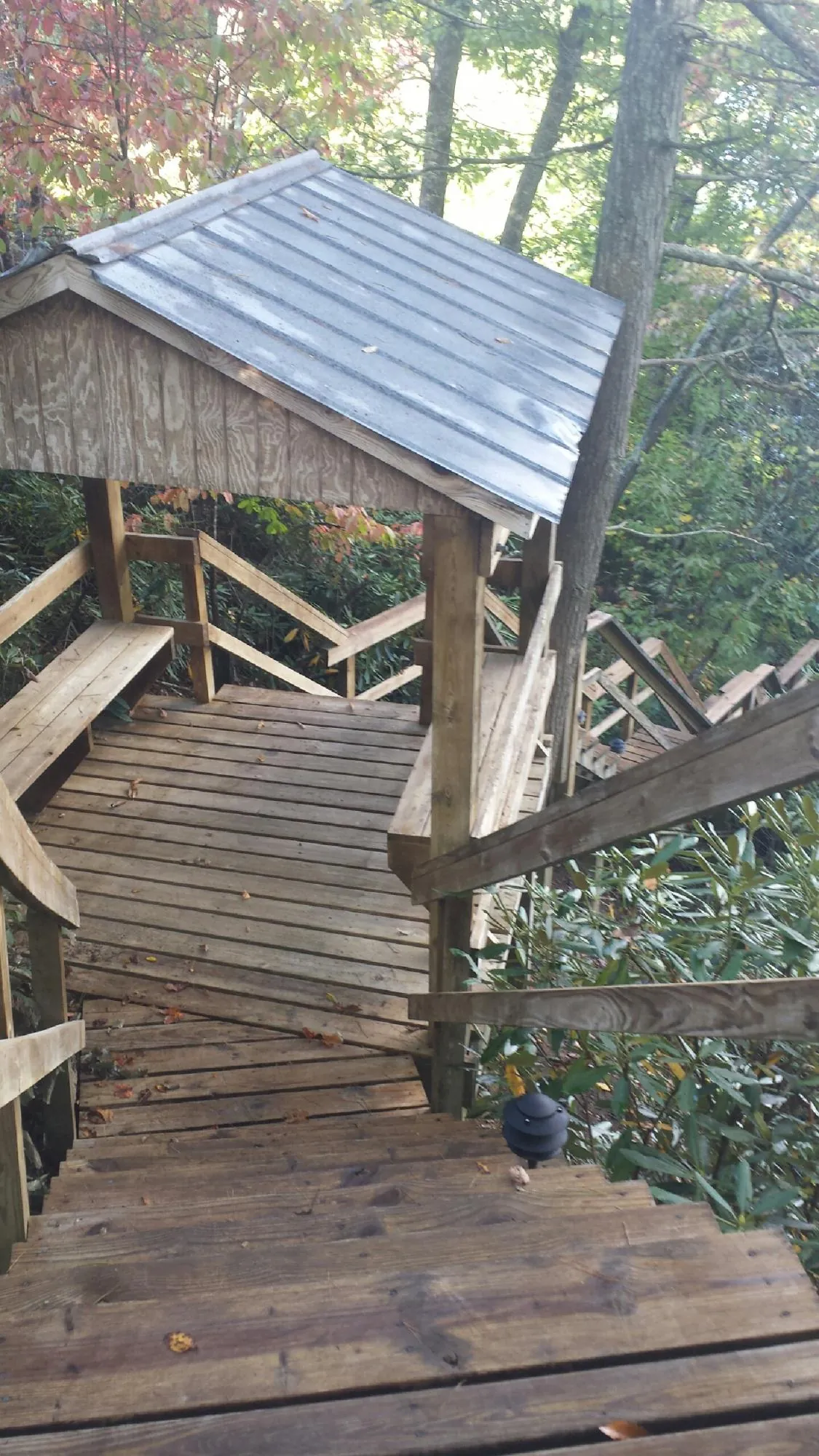 Metal roofed shelter over wooden steps on a wooded walkway — Skylight Repair & Installation work by our crew in Ridgewood