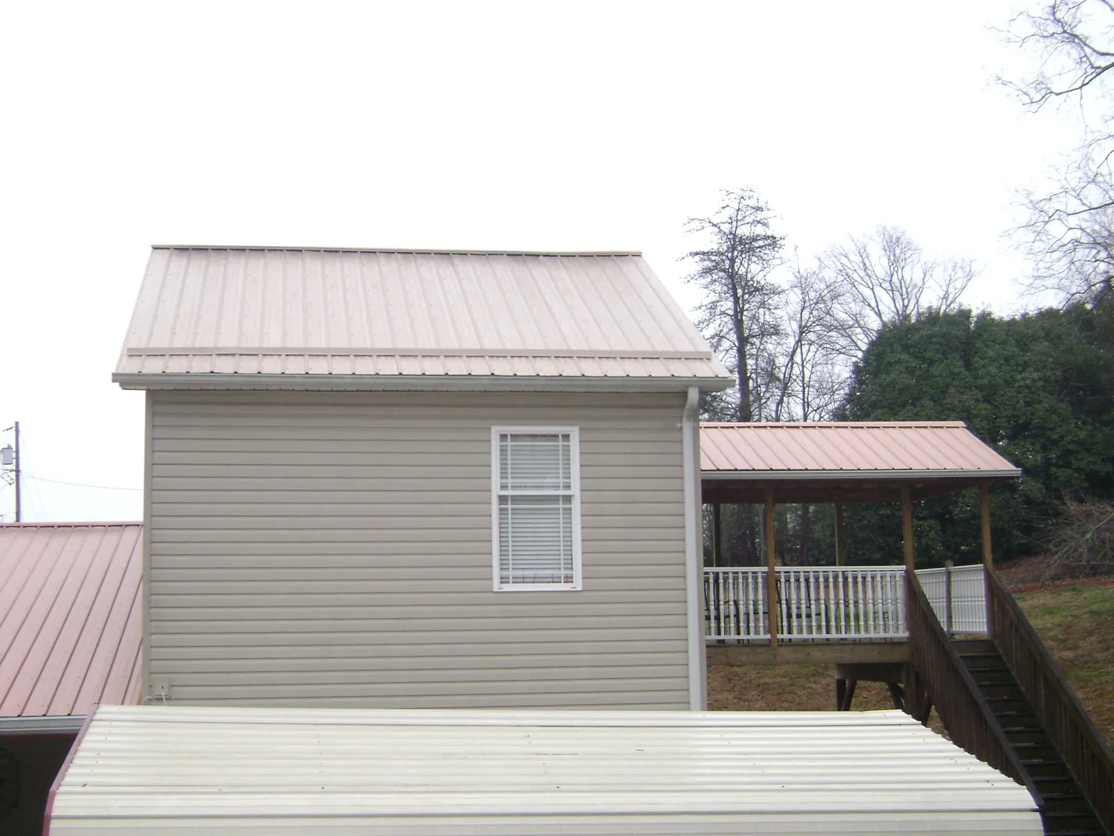 Tan metal roofs on a two story addition and attached porch, from a Roof Replacement job in Ridgewood