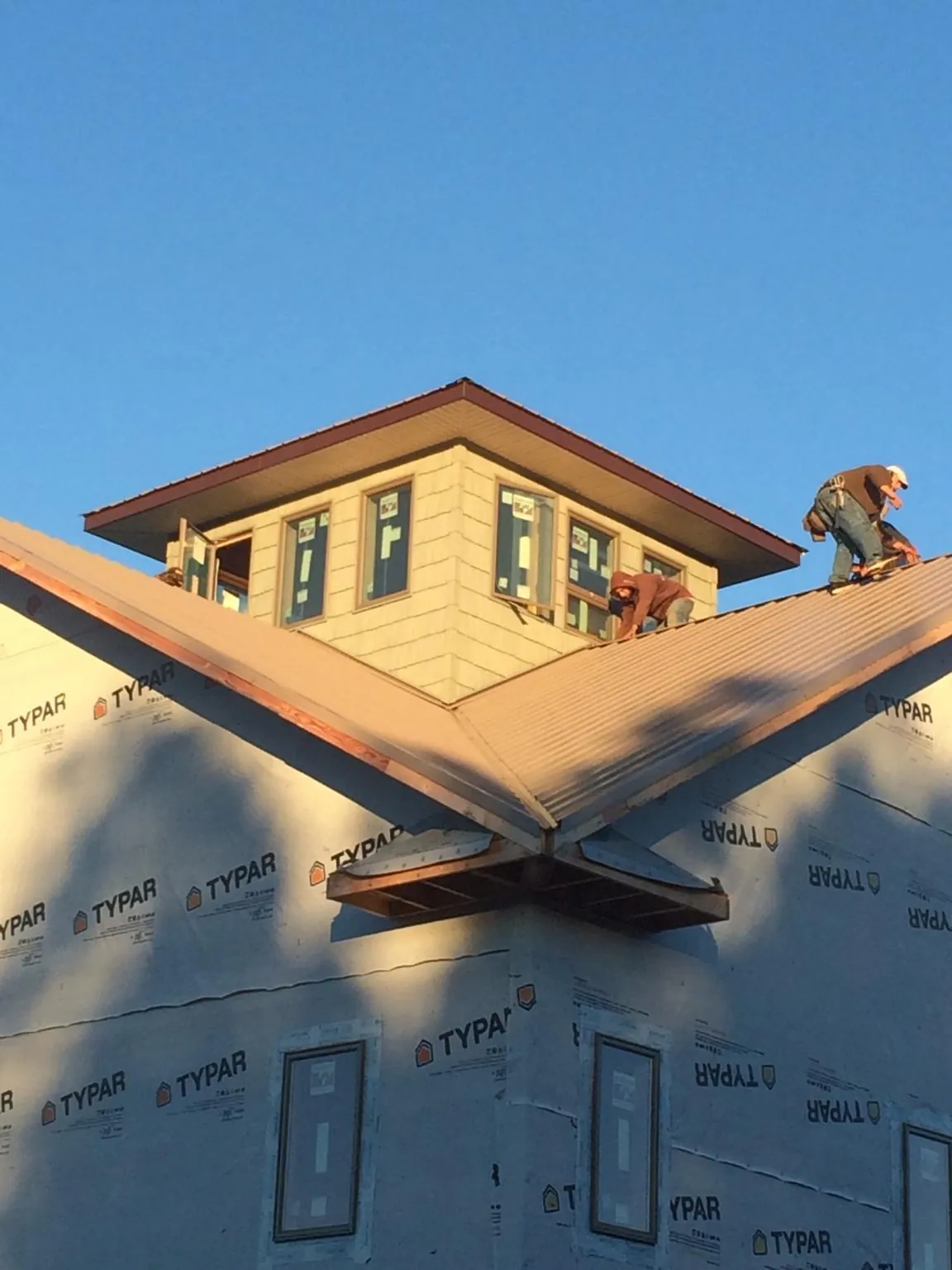 Roofers working around a rooftop cupola on a new metal roof at sunset — Roof Waterproofing in Ridgewood by Roofing Brothers
